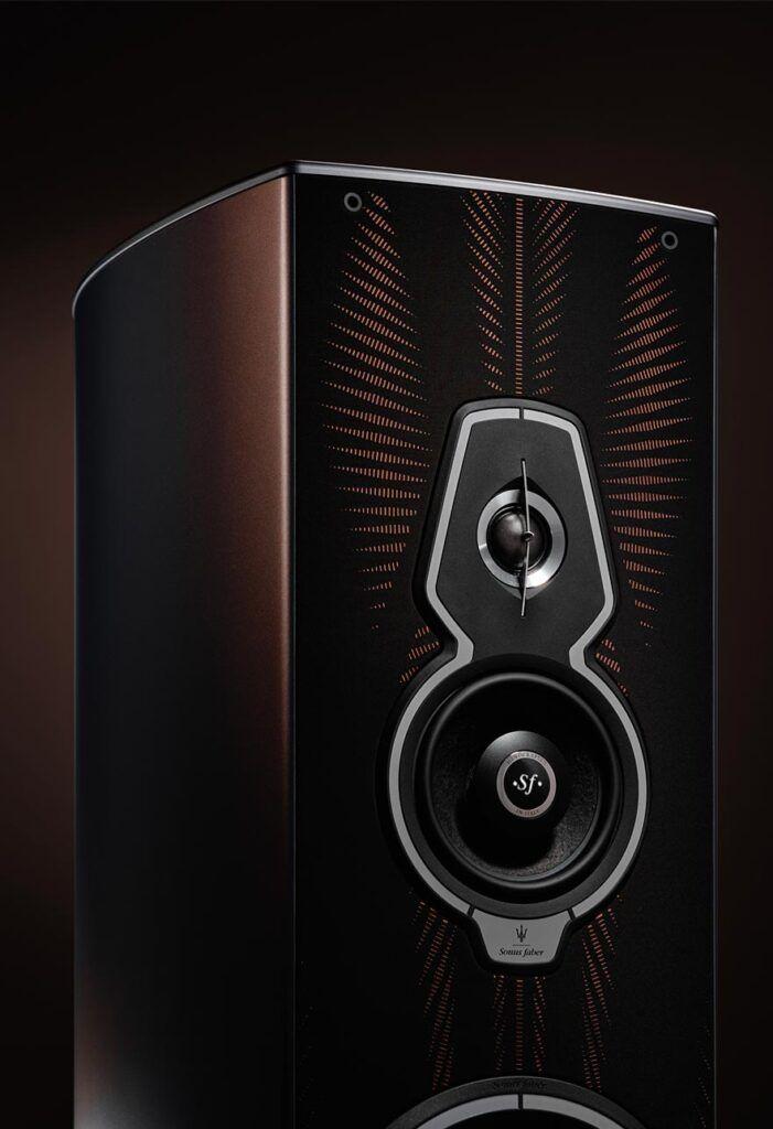 "A detailed view of a Sonus Faber speaker showcasing its intricately designed front panel. Prominently featured is a uniquely shaped mid-range driver with the signature 'SF' logo at its center