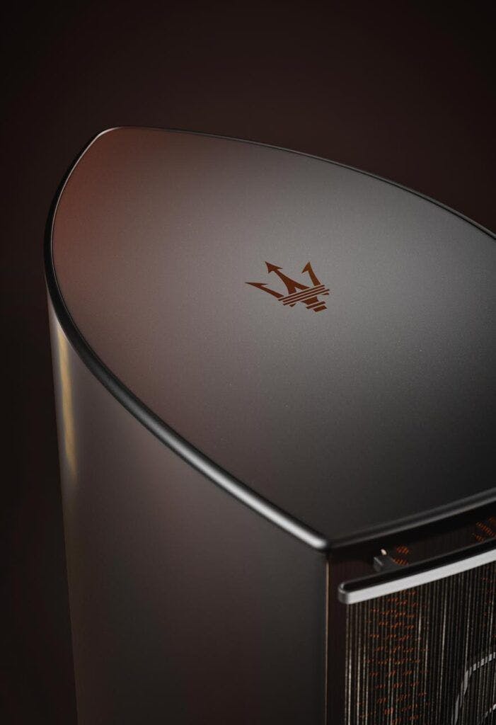A close-up view of the top corner of a Sonus Faber speaker, featuring a delicately engraved emblem resembling a stylized triad of arrows or sails